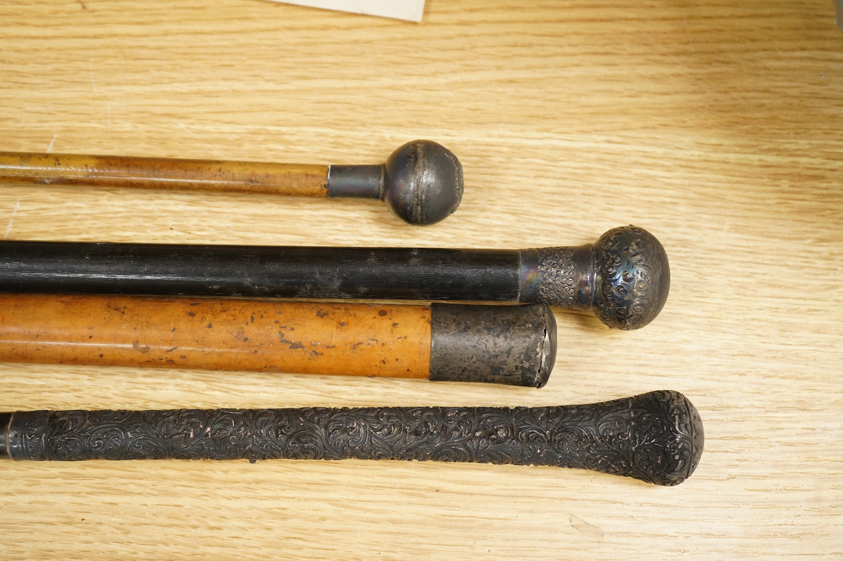 Three silver topped walking canes and a similar parasol, largest 97cm in length